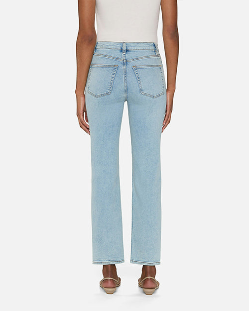 A backside view of a person wearing light blue jeans and a white sleeveless top tucked in. The jeans are high-waisted with two back pockets and straight legs. The person is also wearing sandals.