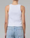 A backside view of a model wearing a white tank top. The model pairs the shirt with light blue jeans.