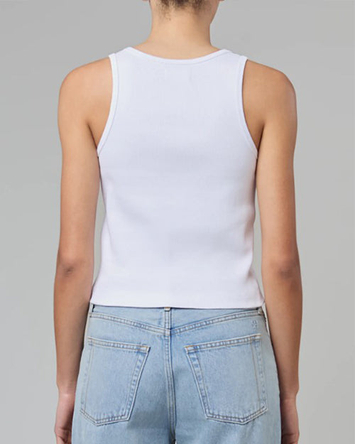A backside view of a model wearing a white tank top. The model pairs the shirt with light blue jeans.