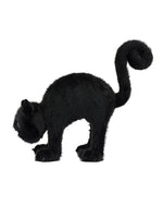 Black plush cat with fluffy fur, arched back, and curled tail, appearing in a startled or defensive posture with forward-facing eyes.