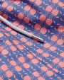 Close-up of purple swim shorts with a pattern of pink crabs. Swim shorts features a white drawstring.