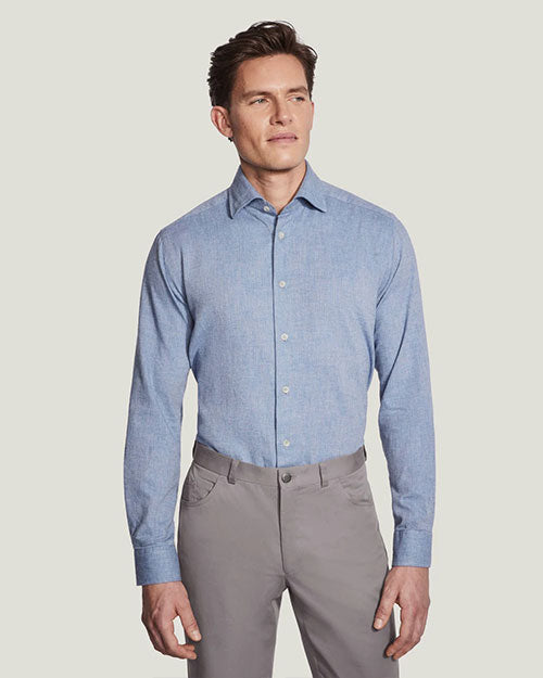 A man dressed in a blue shirt and grey pants poses, embodying a stylish and relaxed look suitable for various occasions.