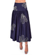 Bottom part of a person wearing a navy blue skirt with white floral patterns and silver heels on a white background 