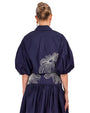 The top back view a person wearing a two piece navy outfit with white floral pattern on a white background