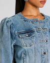 Close up of a button down denim jacket showing all the details like a small pocket with button closure.