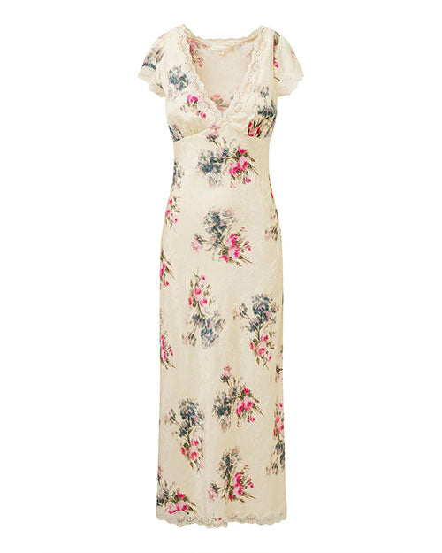 A knee-length dress with a floral pattern on a white background. The dress features short sleeves, a V-neckline, and lace trim detailing. The floral pattern consists of pink and green tones with hints of blue, giving the dress a delicate and feminine appearance.