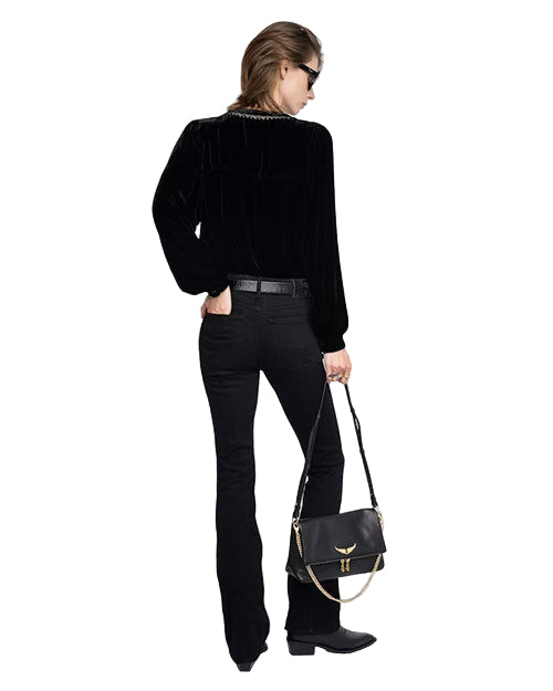 Back view of a person wearing a black long-sleeve top, black pants, and black shoes, holding a black handbag with gold accents in the left hand. 