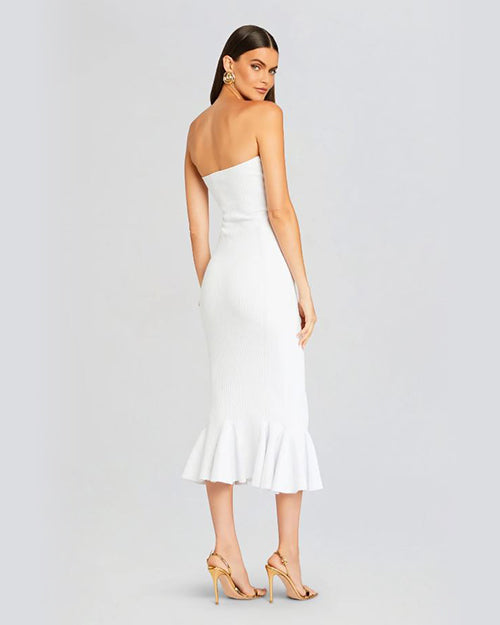 Back view of a person wearing a white strapless midi dress with a flared hemline, paired with gold high-heeled sandals.