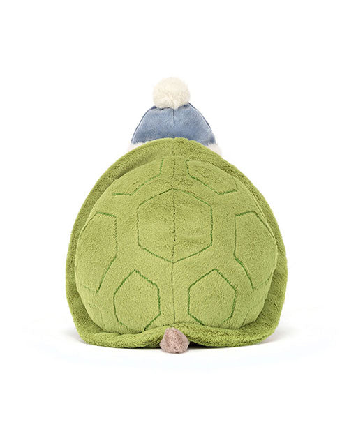 Plush turtle toy with a green shell featuring stitched hexagonal patterns, a small tail, and a blue hat with a white pom-pom on top.