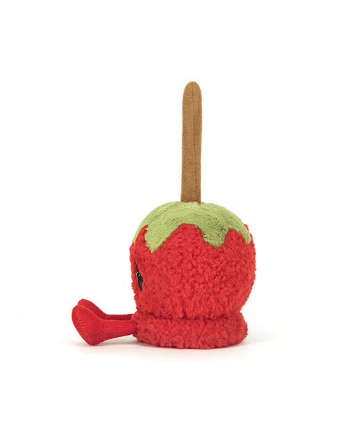 Side view of a Plush toy designed to look like a candy apple, featuring a red textured body, green caramel-like detailing at the top, and a brown stick protruding from the top, resembling a traditional candy apple.