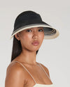Woman wearing a black and beige sun hat on a plain background