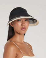 Woman wearing a black and beige sun hat on a plain background