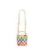 Small woven handbag with a drawstring closure, short handle, and long adjustable strap; features a colorful pattern with green, blue, pink, red, and beige strips.
