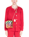 Person in a red outfit with heart-shaped buttons and front pockets, carrying a small colorful woven handbag with a gold shoulder strap.