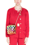Person in a red outfit with heart-shaped buttons and front pockets, carrying a small colorful woven handbag with a gold shoulder strap.