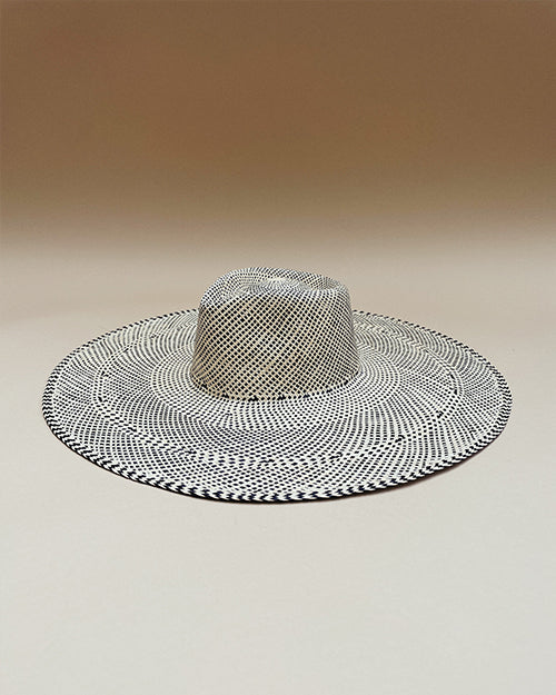 The wide-brimmed hat features a black and white weave pattern that creates a optical illusion effect. The hat has a prominent crown in the center.