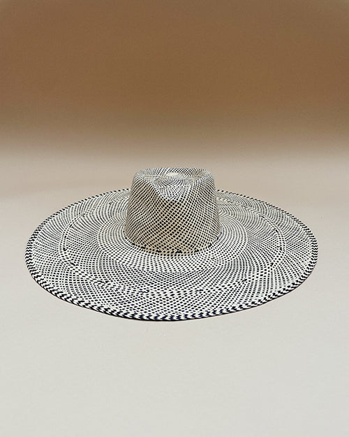 The wide-brimmed hat features a black and white weave pattern that creates a optical illusion effect. The hat has a prominent crown in the center.
