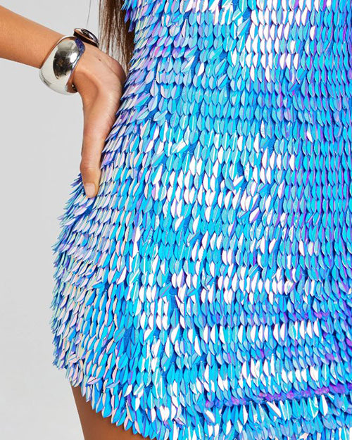 Close up of a feather shaped sequin iridescent blue dress on a person.