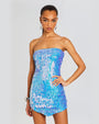 A person wearing a strapless, sequin iridescent blue dress. The hem of the dress is asymmetrical. 