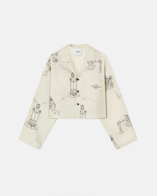 An off-white, long-sleeve button-up pajama shirt. The shirt is off-white with black line drawings of various A person is seen wearing a matching pajama set consisting of a long-sleeve button-up shirt and pants. The pajama set is off-white with black line drawings of various whimsical characters and scenes such as warriors on horses and towers. The background is plain white.