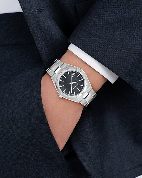 Silver watch on a person's wrist with a dark suit background