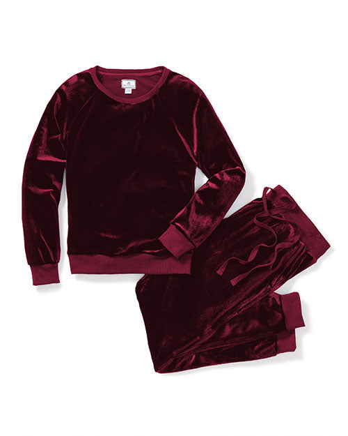 A navy red velvet sweatshirt and matching pants are laid out on a white surface. The sweatshirt has a round neckline and long sleeves, while the pants appear to have an elastic waistband and a relaxed fit. The plush texture of the velvet fabric is visible, giving the clothing a luxurious and comfortable look.