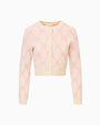 Light-colored long-sleeved cardigan with pink bow patterns, round neckline, front buttons, and two small pockets on the lower front, displayed against a plain white background.