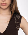 A close-up shot of a brunette models' shoulder wearing a brown V-neck shirt with a Western bedazzled detail at the top. The background is plain white.