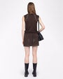 A full body backside view of a brunette model wearing a matching set including a brown tank-top with white rhinestone details at the shoulders, and a short skirt. She is also a black purse with multiple charms hanging from it, and black chunky boots. The background is plain white.