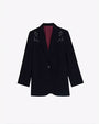 A full view of a black blazer with white embroidery on the shoulders, and a maroon-colored inside. The background is plain white.