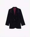 A full view of a black blazer with white embroidery on the shoulders, and a maroon-colored inside. The background is plain white.