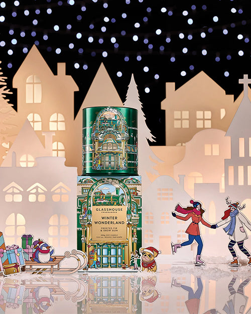 Decorative Christmas scene with a green candle and box  labeled 'Winter Wonderland' against a festive village backdrop.