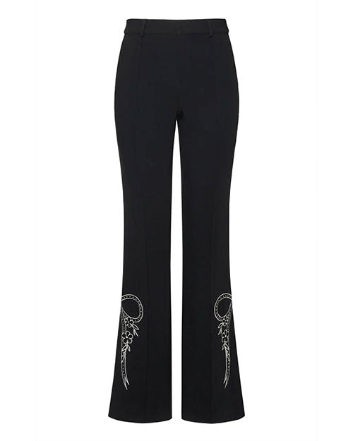 Front view of black tailored trousers with a slim fit through the thigh and subtle flare at the hem, featuring white embroidered bow and floral detailing near the lower legs, displayed against a white background.
