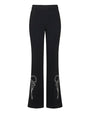 Front view of black tailored trousers with a slim fit through the thigh and subtle flare at the hem, featuring white embroidered bow and floral detailing near the lower legs, displayed against a white background.