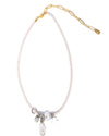 A delicate necklace with small white beads and a gold chain extender, featuring silver charms and a clear teardrop pendant clustered at the center, displayed on a white background.