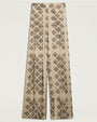 Cream-colored wide-leg trousers featuring an allover black floral-inspired geometric print. The high-waisted trousers have front pleats  and a relaxed, flowing silhouette. 