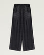 Front view of black wide-leg pants with a subtle metallic sheen and textured finish. The pants feature a flat waistband, a relaxed fit through the hips and legs, and a cropped-to-ankle length silhouette. Displayed against a light gray background.