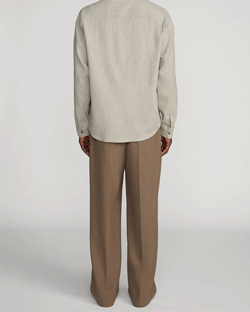 Back view of taupe straight-leg trousers with a relaxed fit and pressed leg creases. The trousers are paired with a light beige textured long-sleeve shirt featuring a subtle vertical stripe pattern and button cuffs. Shown from the shoulders to the feet against a light gray background.