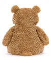 Rear view of a plush teddy bear with light brown, fluffy fur, sitting upright. The bear’s rounded ears, arms, and back are visible, with a slightly rounded bottom.