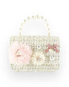 Small handbag with a textured tweed-like fabric in light beige tones, decorated with pink and cream floral embellishments, a pink bow, and a pearl charm, featuring a short handle made of pearl beads.