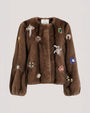Brown fur-textured jacket embellished with jeweled floral and starburst appliqués, featuring a collarless neckline and voluminous sleeves.