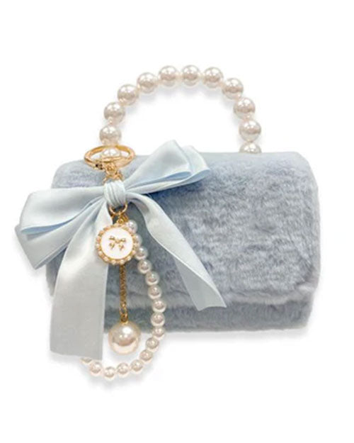 Small light blue faux fur handbag with a pearl handle, decorated with a large satin bow and a dangling charm featuring pearls and a round white medallion with a gold rim.