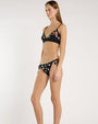 Image of a person's torso, wearing a scalloped black bikini top embroidered with green leaves and pink and purple flowers. 