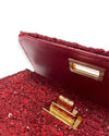 Close-up of the interior of a burgundy tweed handbag with sequins, showing a gold-tone twist-lock closure and matching burgundy lining.