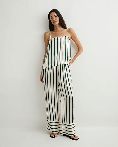 Person modeling a loose, cream-colored camisole and wide-leg pants set with vertical green stripes, paired with black sandals against a plain light background.