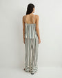 Rear-view of a person modeling a loose, cream-colored camisole and wide-leg pants set with vertical green stripes, paired with black sandals against a plain light background.