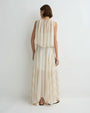 Back view of a person wearing a soft cream sleeveless top with a gathered neckline and layered, flowy fabric, paired with a matching long, airy skirt, against a plain light background.