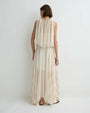 Back view of a person wearing a soft cream sleeveless top with a gathered neckline and layered, flowy fabric, paired with a matching long, airy skirt, against a plain light background.