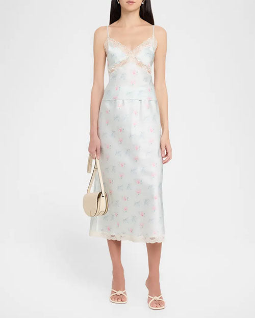 Light green floral slip dress with thin straps, lace-trimmed V-neck bodice, fitted silhouette, and midi-length hem, styled with a small top-handle bag and sandals.