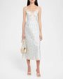 Light green floral slip dress with thin straps, lace-trimmed V-neck bodice, fitted silhouette, and midi-length hem, styled with a small top-handle bag and sandals.